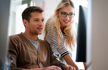 Co-workers reviewing data on a computer screen to develop scalable business solutions