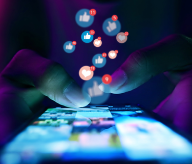 Hands using a smartphone with social media notification icons, illustrating the importance of a social media policy.