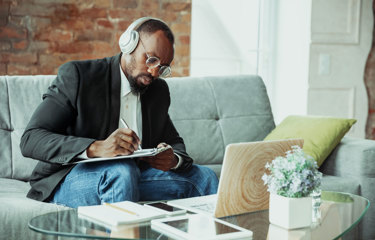 Man taking notes with his headphones on