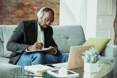 Man taking notes with his headphones on