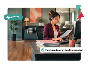 HR professional reviewing documents at desk – update policies and payroll for April 2026 Employment Rights Act changes