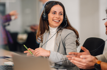 Friendly customer support agent smiling while assisting a client via phone